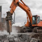 Гидромолот Atlas Copco на экскаваторе дробит бетон на стройке
