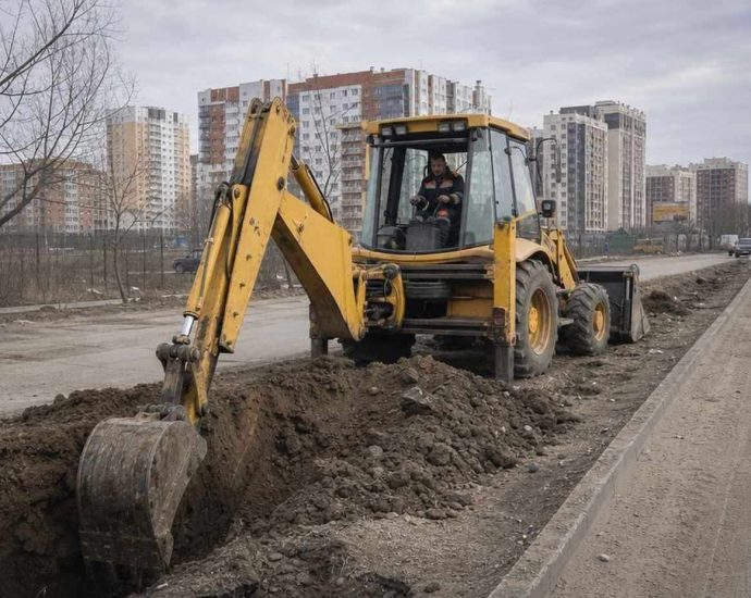 Б/у экскаватор-погрузчик копает траншею на строительной площадке