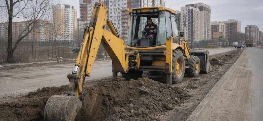 Б/у экскаватор-погрузчик копает траншею на строительной площадке