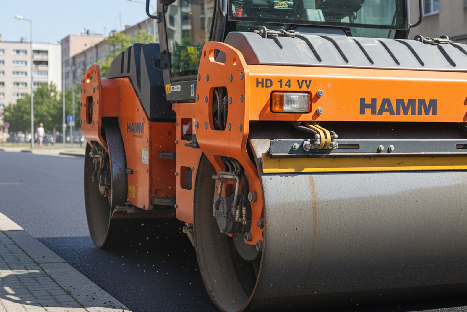 Каток Hamm HD 14 VV работает на тротуаре города, процесс уплотнения асфальта