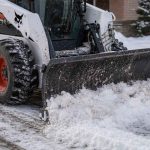 Мини-погрузчик Bobcat расчищает снег во дворе