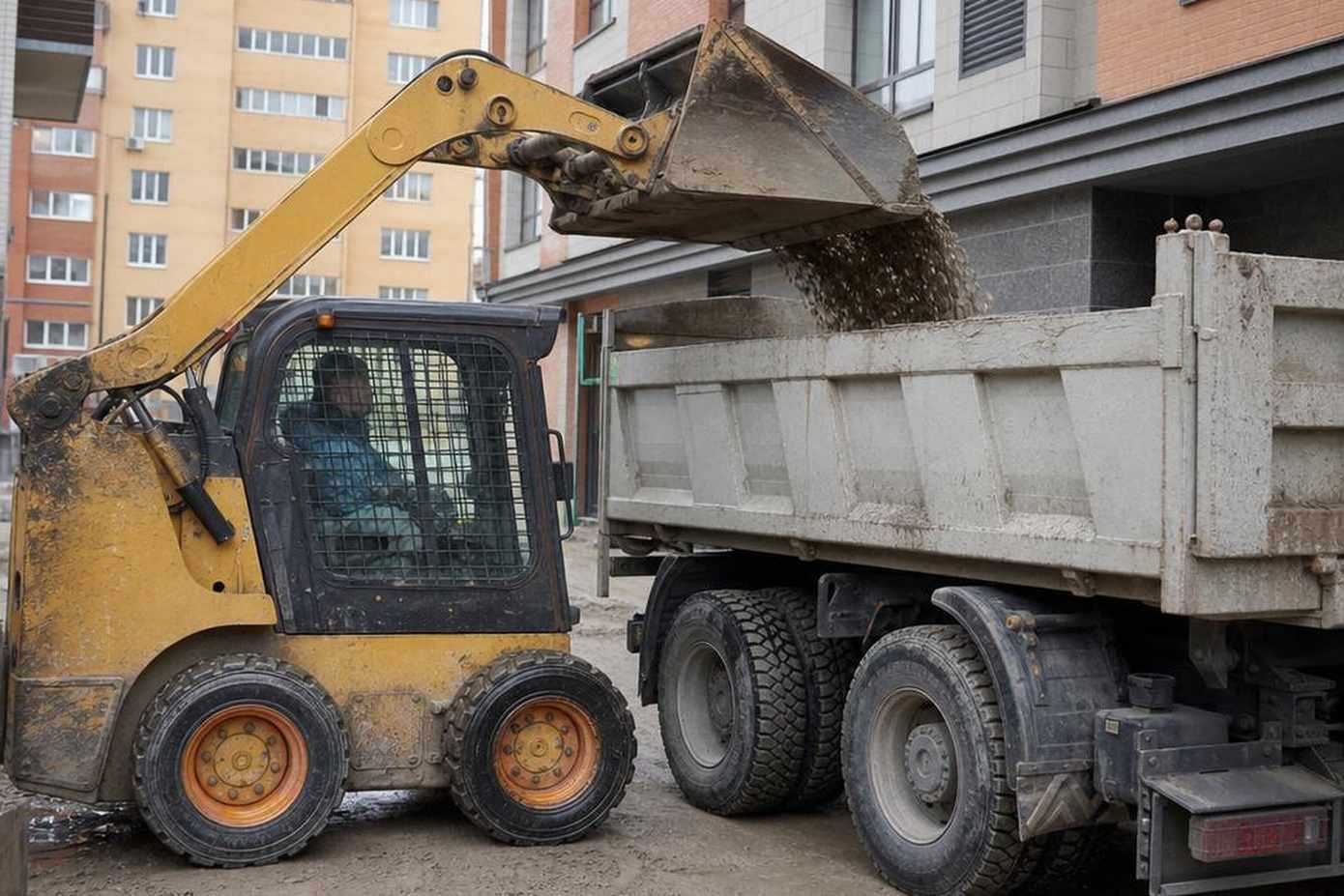 Мини-погрузчик skid-steer на стройплощадке с ковшом