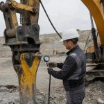 механик проверяет манометром гидромолот на экскаваторе